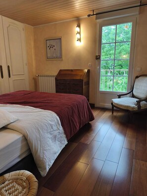 A bedroom with a bed, a dresser, a chair, and a window with a view of greenery.