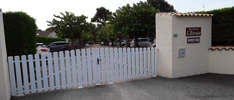 A gated entrance with a white picket fence, a sign reading "Residence L'Escale," and a number "193" indicating the property.
