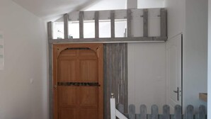 A wooden door with a metal handle, a white picket fence, and a staircase leading to a landing.