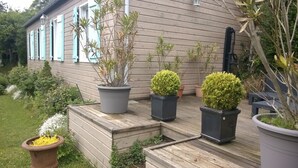 A wooden deck with potted plants and a bench. - Charming cottage 200 meters from the beach, in beautiful wooded property (Veulettes-sur-Mer)