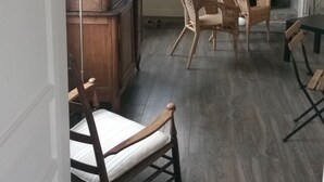 A room with a fireplace, wicker chairs, a tall lamp, and a mirror on the wall. - Charming cottage 200 meters from the beach, in beautiful wooded property (Veulettes-sur-Mer)