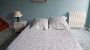 Ein Schlafzimmer mit Bett, Nachttisch, Lampe, Heizkörper und einem Bild an der Wand.