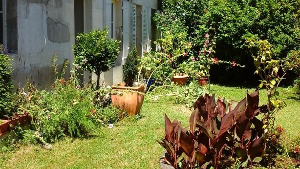 Ein zweistöckiges Gebäude mit einem Garten davor.