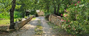 A gravel path flanked by stone walls and lush greenery, leading to a stone building. - Exceptional setting for a villa with 4,800 m² of land (Fayence)