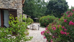 A stone patio with a table and chairs, surrounded by lush greenery and flowering plants. - Exceptional setting for a villa with 4,800 m² of land (Fayence)