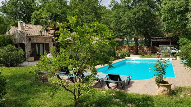 A swimming pool with lounge chairs, surrounded by lush greenery and a stone building. - Exceptional setting for a villa with 4,800 m² of land (Fayence)
