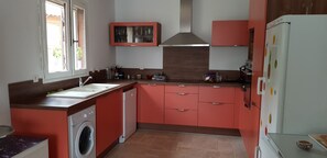A kitchen with a washing machine, a sink, and a refrigerator.