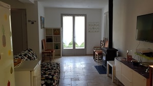 A compact living space with a kitchenette, a sofa, a television, and a sliding glass door leading to a balcony. - Exceptional setting for a villa with 4,800 m² of land (Fayence)