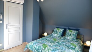 A bedroom with a bed, nightstands, a wall-mounted air conditioner, and a door.