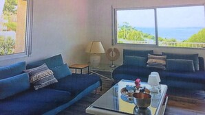 A living room with two blue sofas, a glass coffee table, a lamp, and a view of the sea. - BEAUTIFUL APARTMENT WITH SEA VIEW TERRACE- NEAR BEACH - IDEAL FAMILY HOLIDAYS (Roses)