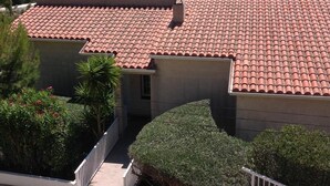 A coastal house with a tiled roof, a small garden, and a view of the sea. - BEAUTIFUL APARTMENT WITH SEA VIEW TERRACE- NEAR BEACH - IDEAL FAMILY HOLIDAYS (Roses)