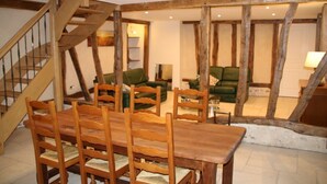 A dining area with wooden furniture, a staircase, and exposed wooden beams. - House completely renovated in the countryside in tourist village (Saint-Evroult-Notre-Dame-du-Bois)