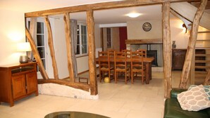 A room with exposed wooden beams, a dining table with chairs, a green sofa, and a lamp. - House completely renovated in the countryside in tourist village (Saint-Evroult-Notre-Dame-du-Bois)