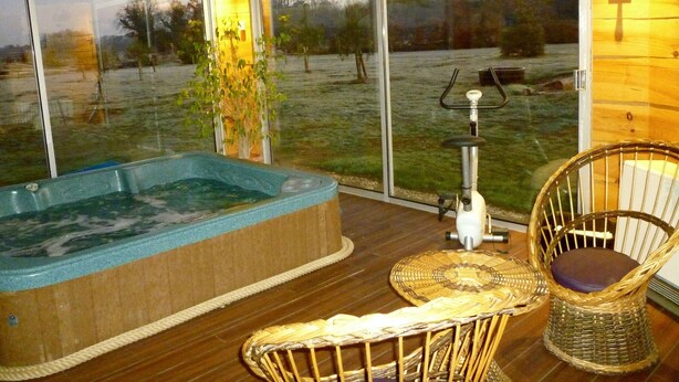 Un jacuzzi con vistas a un campo cubierto de hierba, una silla de mimbre y una bicicleta.