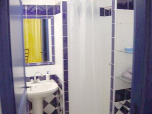 A bathroom with a white sink, a mirror, and a yellow curtain.