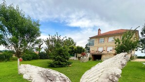 A stone angel sculpture in a grassy area with a house in the background. - House of Lacaze 2 ears (Toulonjac)
