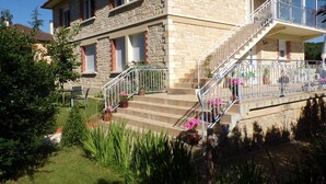 A two-story stone building with a balcony, a staircase, and potted plants. - House of Lacaze 2 ears (Toulonjac)
