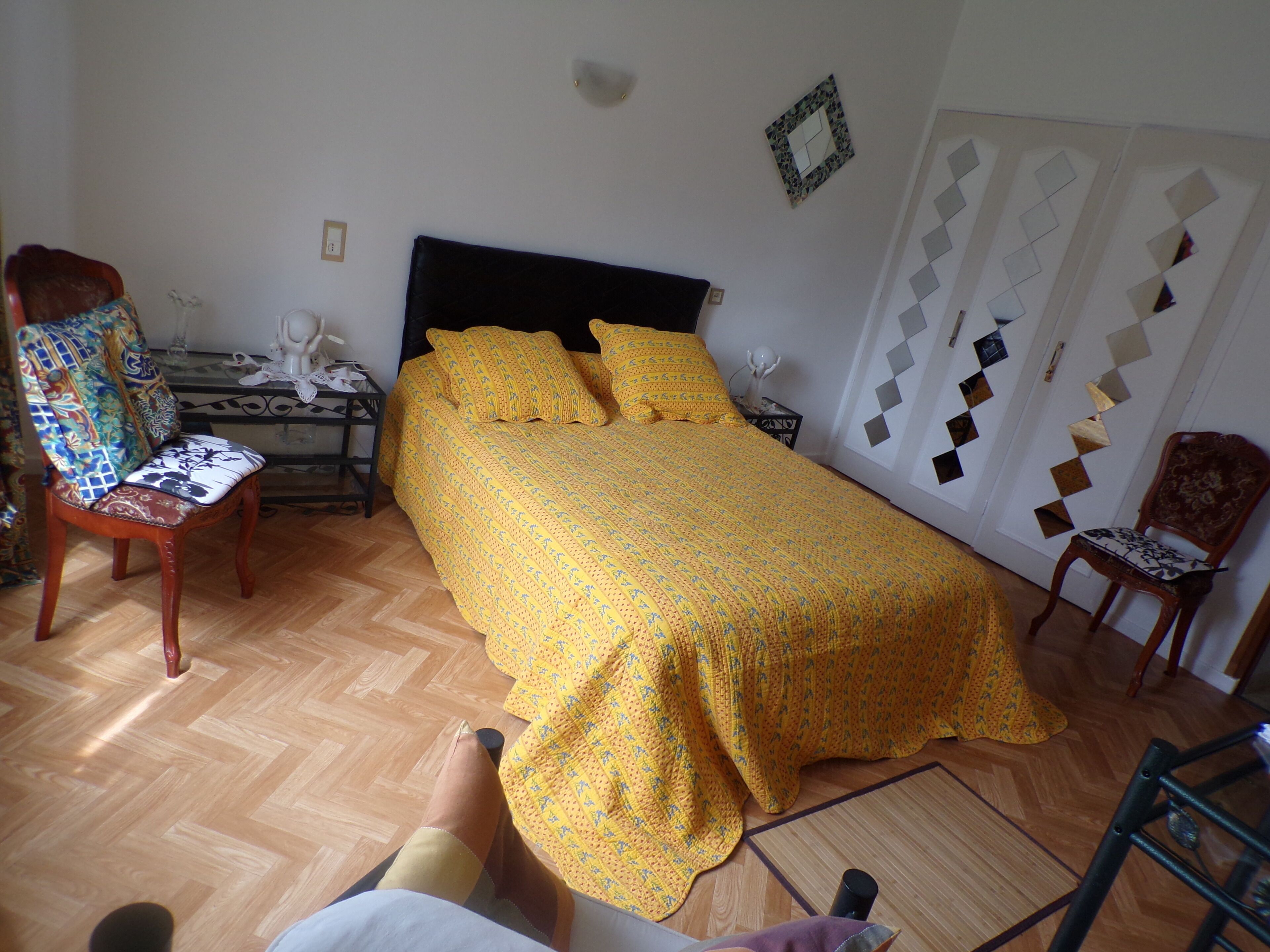 Ein Schlafzimmer mit einem Bett, zwei Stühlen, einem Nachttisch und einer Wandleuchte.