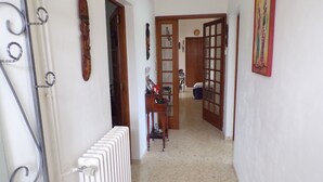 A hallway with a radiator, wooden doors, and a painting on the wall. - House of Lacaze 2 ears (Toulonjac)