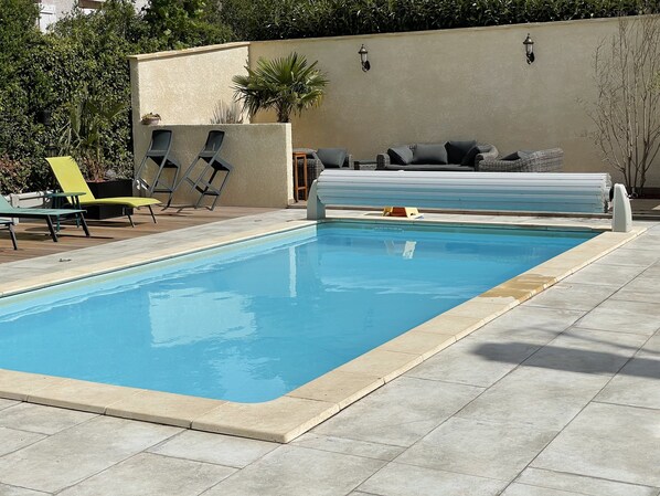 A swimming pool with lounge chairs and a sofa.