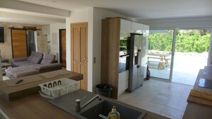 Una cocina moderna con refrigerador empotrado, un lavamanos y una zona de comedor con mesa y sillas.