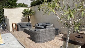 Un patio con mobiliario de mimbre, una mesita y una planta en maceta.