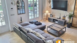Una sala de estar moderna con un sofá gris, una mesa de centro, un televisor y un ventanal grande.