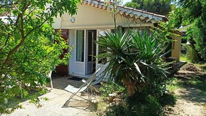 A small, single-story house with a tiled roof, a sliding glass door, and a small patio area with a folding chair. - T2 ground floor Carry le Rouet (Carry-Le-Rouet)