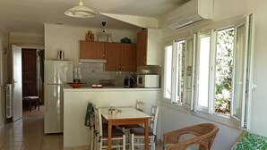 A compact kitchen with a dining area, a refrigerator, a microwave, and a window with a view of greenery. - T2 ground floor Carry le Rouet (Carry-Le-Rouet)