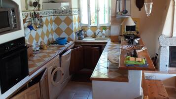 Una cocina con una isla central, armarios de madera, una lavadora y un microondas.