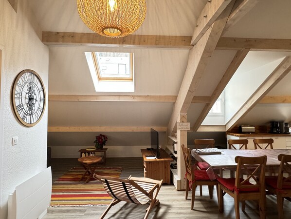 Habitación en el ático con una mesa de comedor, sillas, un reloj y un tragaluz.