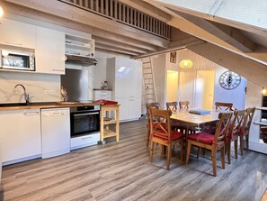 Eine moderne Küche mit weißen Schränken, einem eingebauten Backofen und einem Holzespeisetisch mit Stühlen.