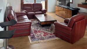A living room with a brown leather sofa, a coffee table, and a TV on a wooden cabinet. - Guirec Dogs (Perros-Guirec)
