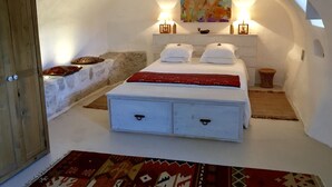 Une chambre à coucher avec un lit, une table de chevet, une lampe, un tableau et une armoire en bois.