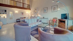 A spacious living room with a high ceiling, a staircase, a television, and a dining area. - DUPLEX EXCEPTIONNEL AVEC VUE MER A1B059 (Cannes)