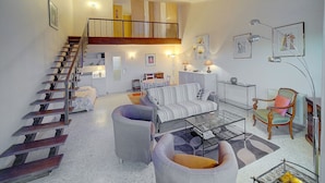 A spacious living area with a staircase, a sofa, a coffee table, and a chair. - DUPLEX EXCEPTIONNEL AVEC VUE MER A1B059 (Cannes)
