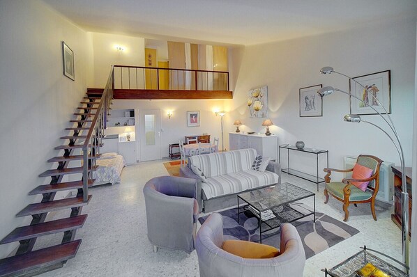 A spacious living area with a staircase, a sofa, a coffee table, and a chair.