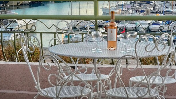 A round table with a bottle and glasses on a balcony overlooking a marina with boats. - DUPLEX EXCEPTIONNEL AVEC VUE MER A1B059 (Cannes)
