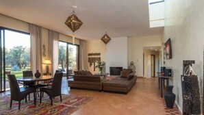 A spacious living area with a large sofa, a dining table with chairs, and a colorful rug. There are two hanging lights and a fireplace. - Villa Kristy Junior (2 bedrooms + Private pool) (Marrakesh)