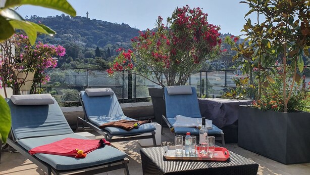 Eine Dachterrasse mit Liegestühlen, einem Tisch mit Getränken und Blumentöpfen.