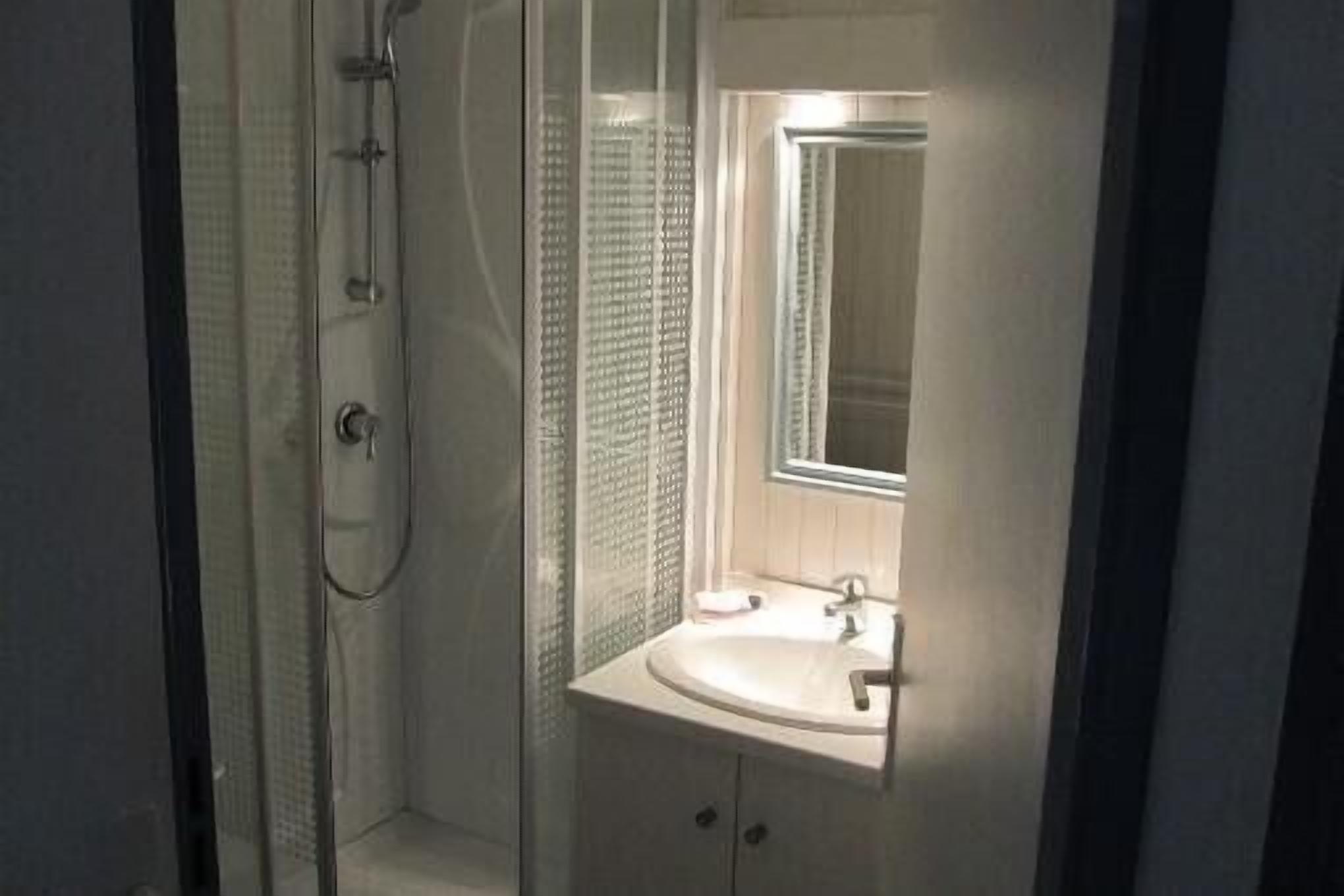 Un baño con ducha envuelta en vidrio, un lavabo y un espejo.
