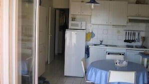 A compact kitchen with white cabinets, a microwave, a refrigerator, and a dining table with chairs. - 6P apartment in Collioures / 10 min from Argelès / Waterfront (Pyrénées-Orientales)