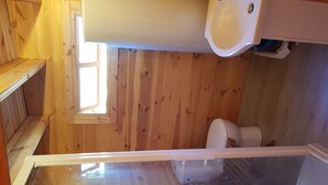 Eine kleine, hölzerne Hütte mit einem Bad, inklusive Toilette und Waschbecken.