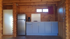 Eine kleine Küche mit einem Kühlschrank, einer Kaffeemaschine und einem Spülbecken.