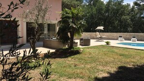 Une maison avec une piscine, un espace extérieur aménagé et un jardin.