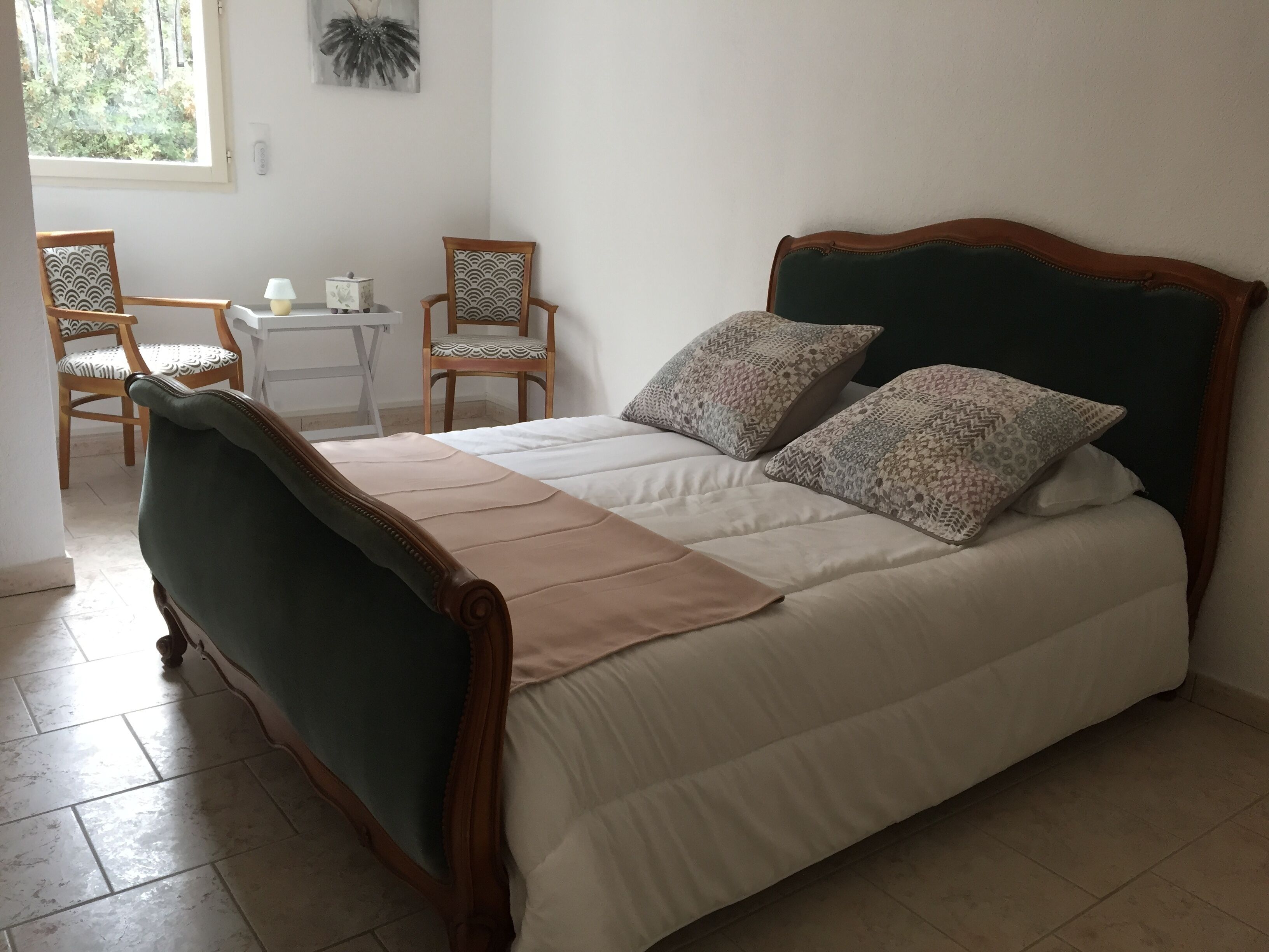 Ein ordentlich eingerichtetes Schlafzimmer mit einem Bett, zwei Stühlen, einem kleinen Tisch und einem Fenster.