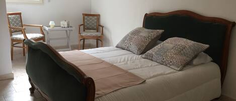 Ein ordentlich eingerichtetes Schlafzimmer mit einem Bett, zwei Stühlen, einem kleinen Tisch und einem Fenster.