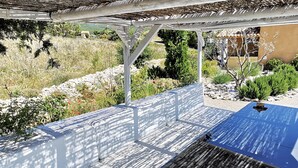 A covered outdoor seating area with a pergola structure, surrounded by a landscaped garden with various plants and a view of a distant landscape. - La Casa, Charming little house of Provence  (Ongles)
