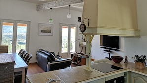 A spacious living area with a dining table, black leather sofa, and a kitchen area with a stove and sink. - La Casa, Charming little house of Provence  (Ongles)