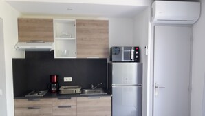 Una cucina compatta con mobili in legno, un frigorifero in acciaio inossidabile, un forno a microonde e una macchina da caffè.